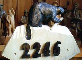 Custom carving  with a beaver over the numbers of a street address